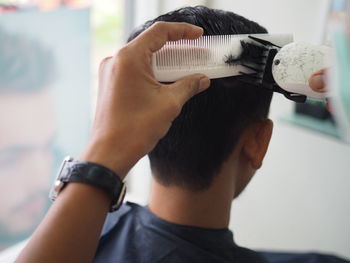Cropped image of barber cutting hair of customer