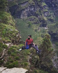 Woman sitting on rock by mountain