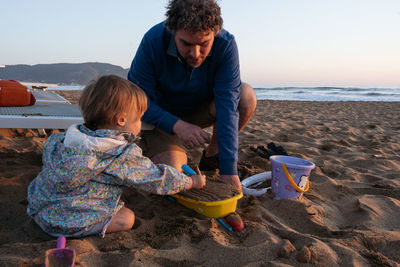 Father and child sitting at the beach in the sunset