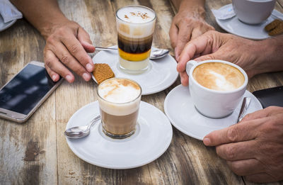 Midsection of man holding coffee cup on table