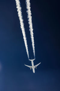 Low angle view of airplane flying against blue sky