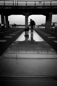 Rear view of silhouette woman walking on bridge