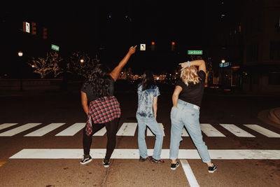 Rear view of people walking on street at night