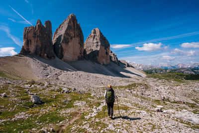Rear view of person on rock by mountains against sky