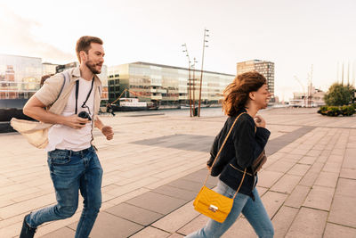 Happy couple running on street while exploring city