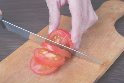 Cropped hand of man holding bell pepper on cutting board