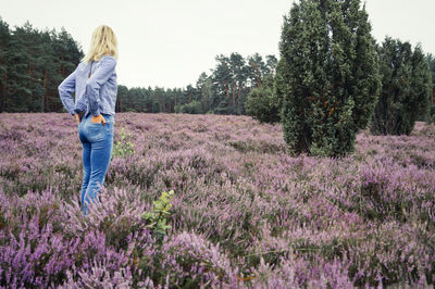 Rear view of woman standing on field against sky