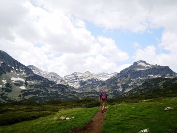 Rear view of man walking on mountain against sky