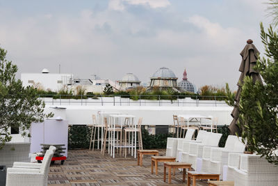 Empty chairs and tables at restaurant against sky