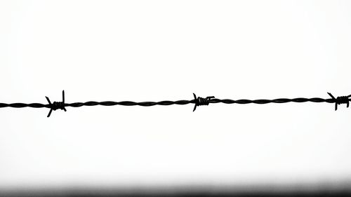 Close-up of barbed wire against clear sky