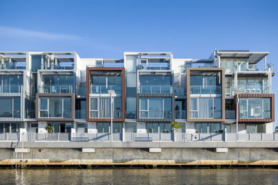 Buildings by river against blue sky