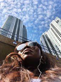 Low angle portrait of woman against buildings in city