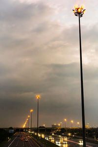 Cars on street against sky at dusk