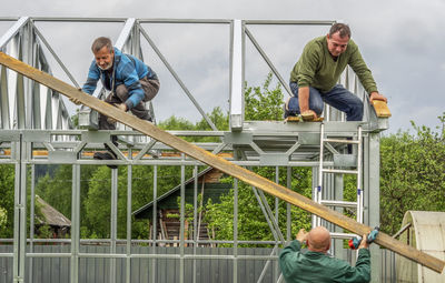 Manual workers making metallic built structure on field