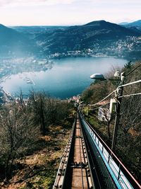 High angle view of railroad track with lake and mountains against sky