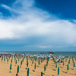 Hooded chairs on beach against sky