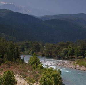 Scenic view of river by mountains against sky