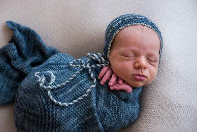 Newborn in a crib in a blue winding and cap