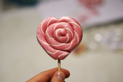 Cropped hand holding heart shape lollipop