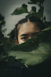 Close-up portrait of boy with leaves in plant