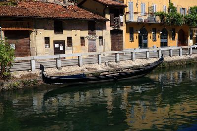 Gondola moored in canal by buildings in city