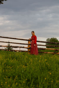 Rear view of woman standing on field against sky