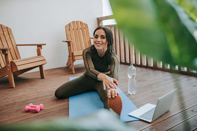 Young woman using phone while sitting on table