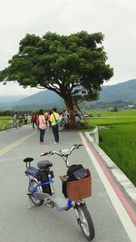 People riding bicycle on road against sky