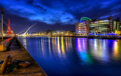 Illuminated samuel beckett bridge over river against sky