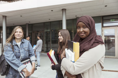 Portrait of student in hijab standing with friends at university campus