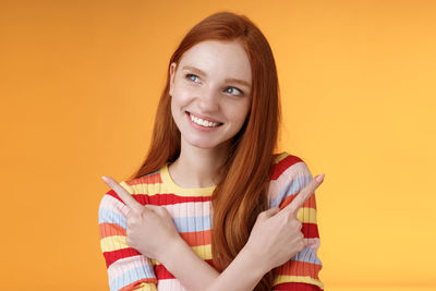 Portrait of a smiling young woman against orange background