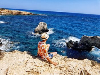 Female rock in sea against sky