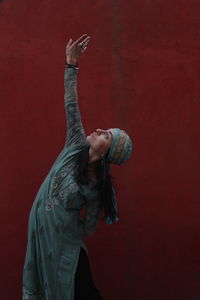 Young woman dancing against wall