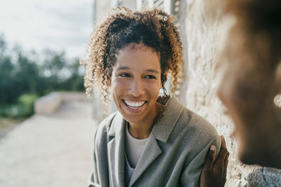 Happy young woman sitting with female friend in backyard