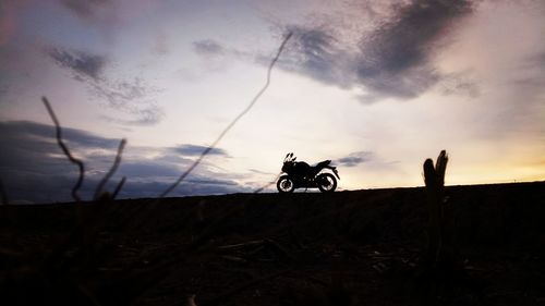 Silhouette man with bicycle against sky during sunset