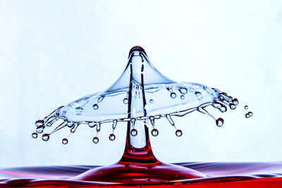 Close-up of drop splashing on water against white background