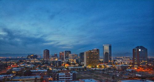 Illuminated buildings in city against sky at dusk