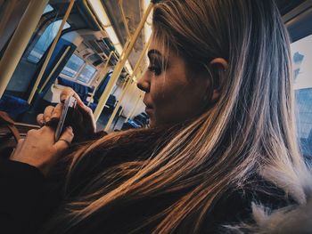 Close-up of woman using mobile phone while sitting in train