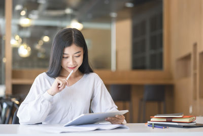 Young woman using mobile phone while sitting on table