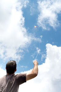 Low angle view of man paragliding against sky