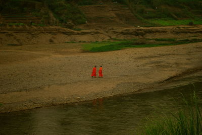 Side view of two monks walking by the lake