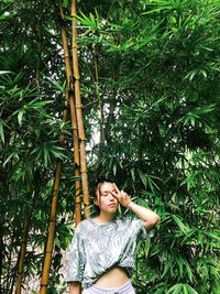 Young woman looking away against trees