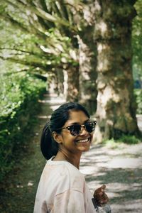 Young woman wearing sunglasses against trees