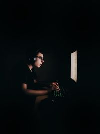 Teenage boy using computer in darkroom