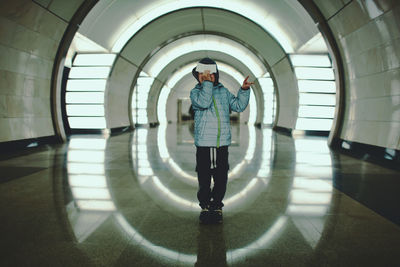 Full length of boy wearing warm clothing standing in illuminated tunnel