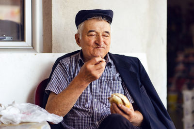 Portrait of man holding food while sitting outdoors