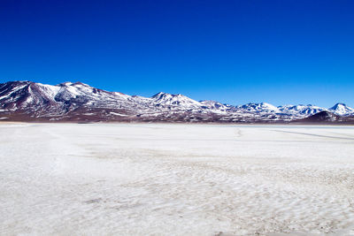 Scenic view of snowcapped mountains against blue sky