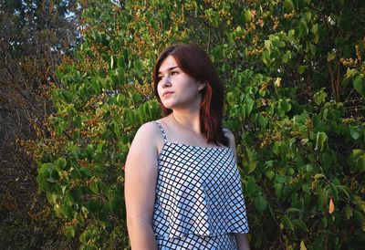 Thoughtful woman standing by tree