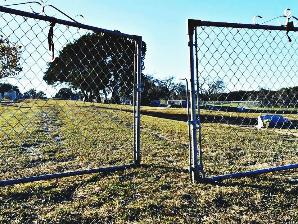 fence, chainlink fence, field, protection, sky, safety, grass, clear sky, metal, security, landscape, day, agriculture, rural scene, tree, grassy, building exterior, no people, outdoors, sunlight