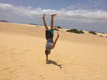 Full length of young woman on beach against sky